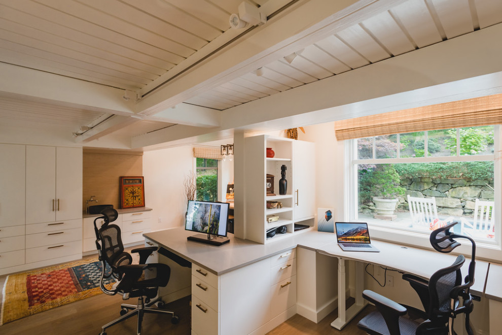 Imagen de despacho contemporáneo con paredes blancas, suelo de madera en tonos medios, escritorio empotrado, suelo marrón, vigas vistas y machihembrado