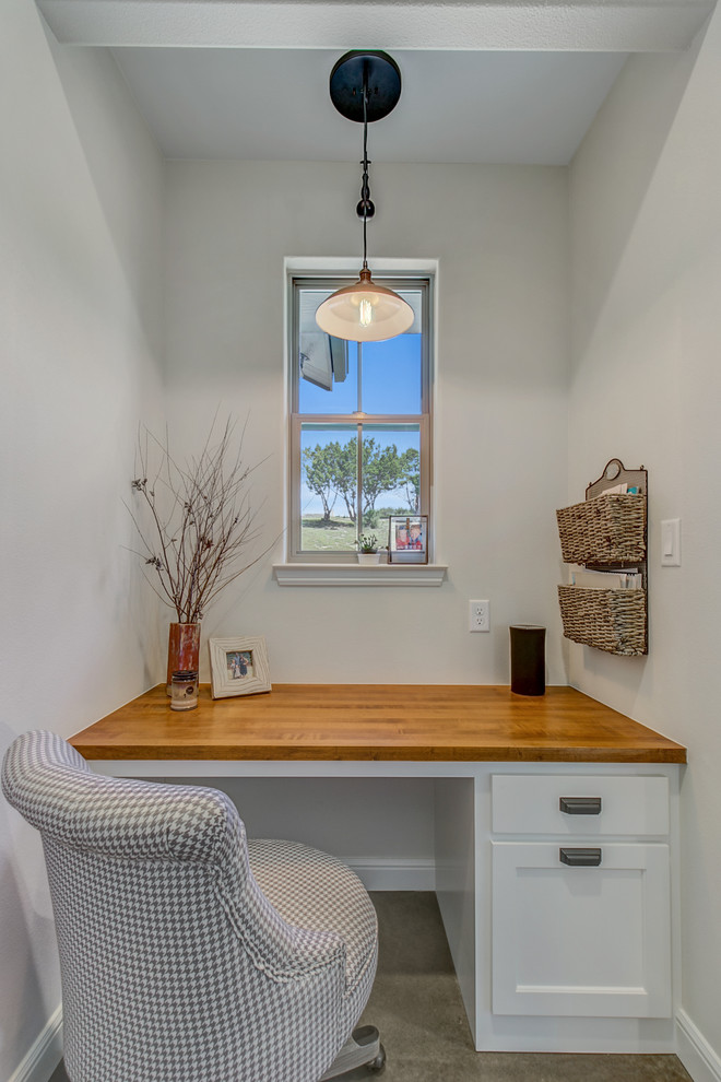 Inspiration for a small farmhouse built-in desk concrete floor study room remodel in Dallas