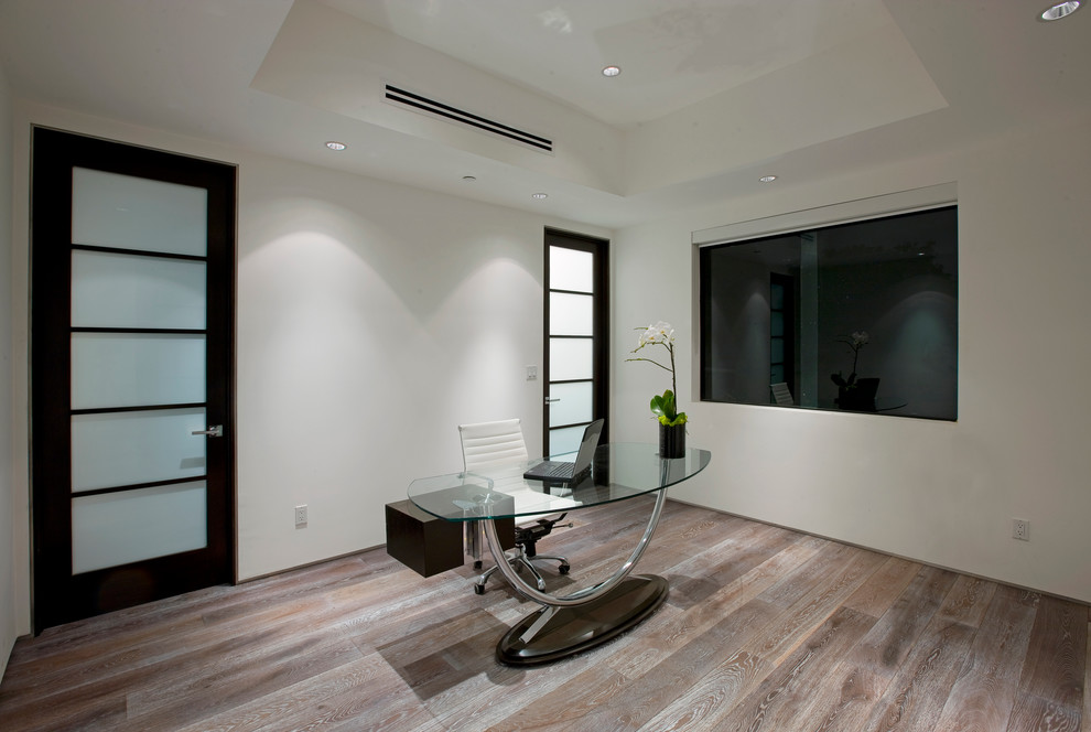 Mittelgroßes Modernes Arbeitszimmer mit weißer Wandfarbe, braunem Holzboden und freistehendem Schreibtisch in Los Angeles