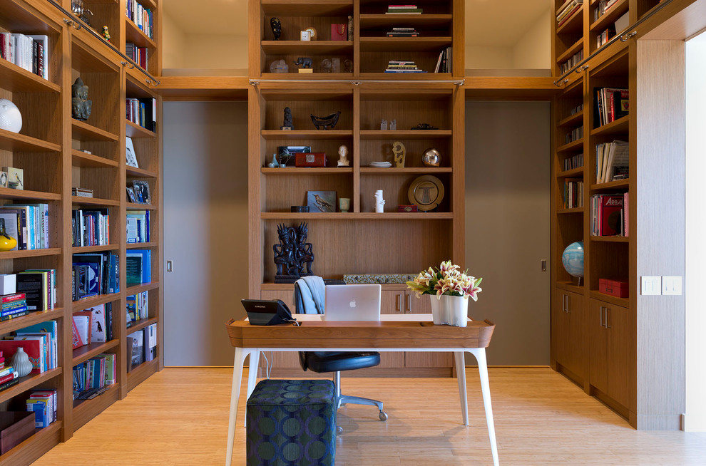 Ejemplo de despacho contemporáneo de tamaño medio sin chimenea con suelo de madera en tonos medios, escritorio independiente, paredes grises y suelo marrón