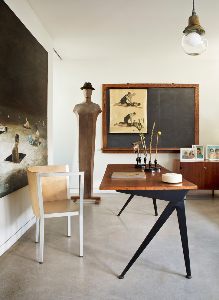Imagen de despacho bohemio con paredes blancas, suelo de cemento y escritorio independiente