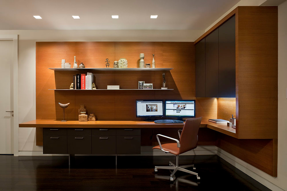 Kleines Modernes Arbeitszimmer mit Arbeitsplatz, weißer Wandfarbe, dunklem Holzboden und Einbau-Schreibtisch in New York