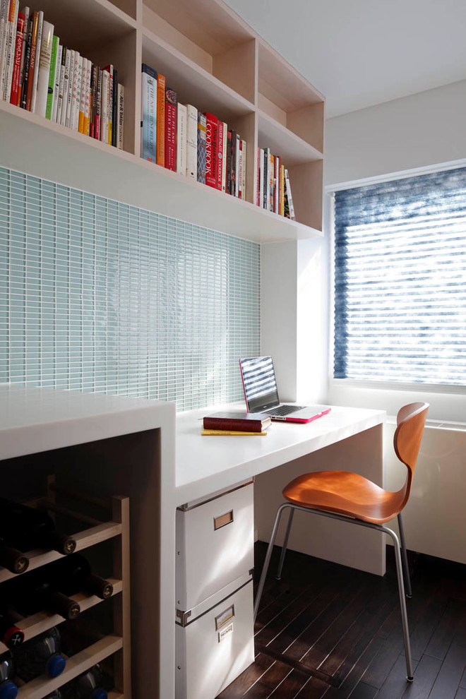 Modelo de despacho contemporáneo pequeño con suelo de madera oscura, paredes azules, escritorio empotrado y suelo marrón