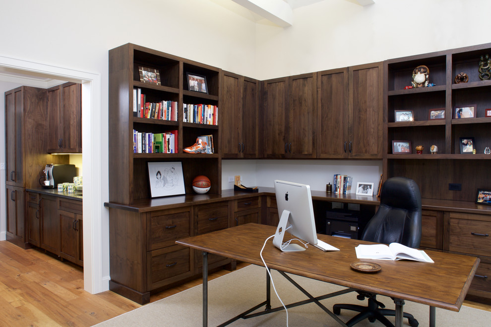 Modelo de despacho tradicional renovado grande con paredes beige, suelo de madera clara y escritorio independiente