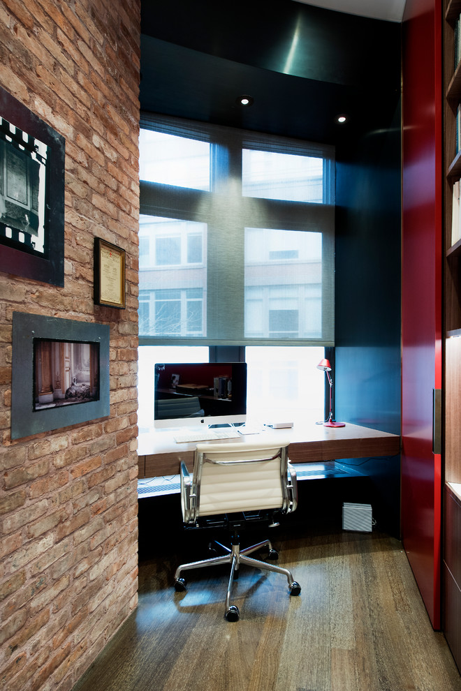 Cette photo montre un petit bureau avec un mur rouge, un sol en bois brun et un bureau indépendant.