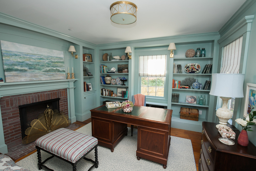 Cette image montre un bureau traditionnel de taille moyenne avec un mur bleu, parquet foncé, une cheminée standard, un manteau de cheminée en brique, un bureau indépendant et un sol marron.