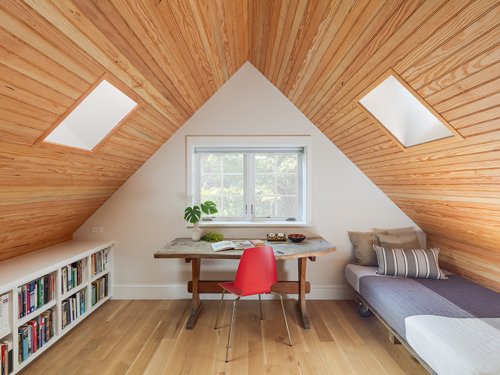 Foto de despacho de estilo de casa de campo sin chimenea con biblioteca, paredes blancas, suelo de madera clara, escritorio independiente y suelo beige