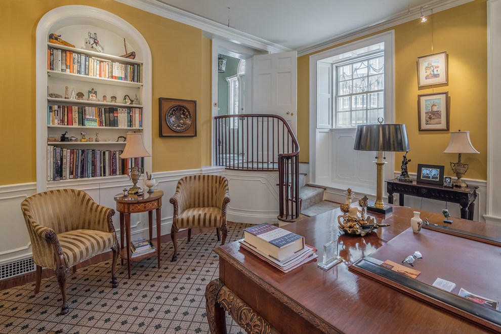 Idéer för vintage hemmabibliotek, med gula väggar, ett fristående skrivbord och mellanmörkt trägolv