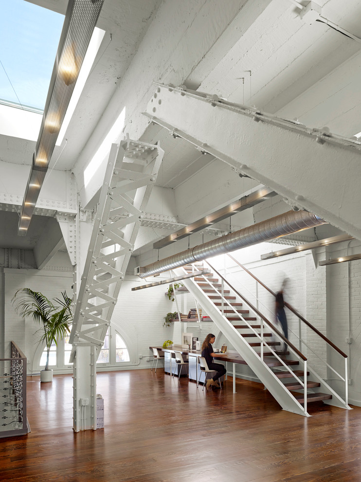 Geräumiges Industrial Arbeitszimmer mit weißer Wandfarbe, braunem Holzboden und Einbau-Schreibtisch in San Francisco