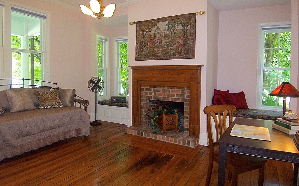 Idéer för att renovera ett mellanstort vintage arbetsrum, med rosa väggar, mellanmörkt trägolv, en standard öppen spis, en spiselkrans i tegelsten, ett fristående skrivbord och brunt golv