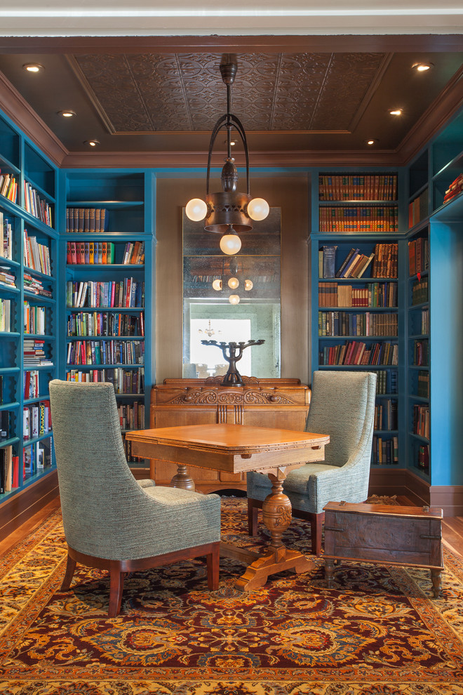 Klassisk inredning av ett mellanstort arbetsrum, med ett bibliotek, blå väggar och mörkt trägolv