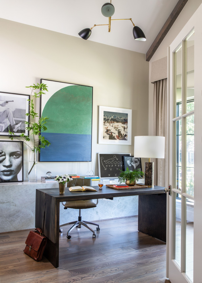 Mittelgroßes Klassisches Arbeitszimmer ohne Kamin mit Arbeitsplatz, beiger Wandfarbe, braunem Holzboden, freistehendem Schreibtisch und braunem Boden in Houston