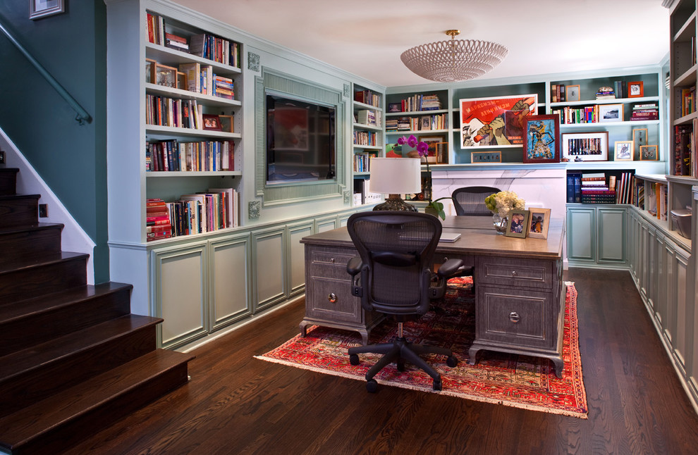 Klassisk inredning av ett mellanstort hemmabibliotek, med blå väggar, mörkt trägolv och ett fristående skrivbord