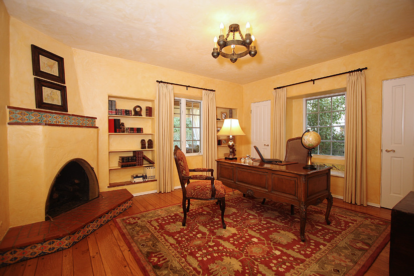 Immagine di un ufficio chic di medie dimensioni con pareti beige, pavimento in legno massello medio, camino ad angolo e scrivania autoportante