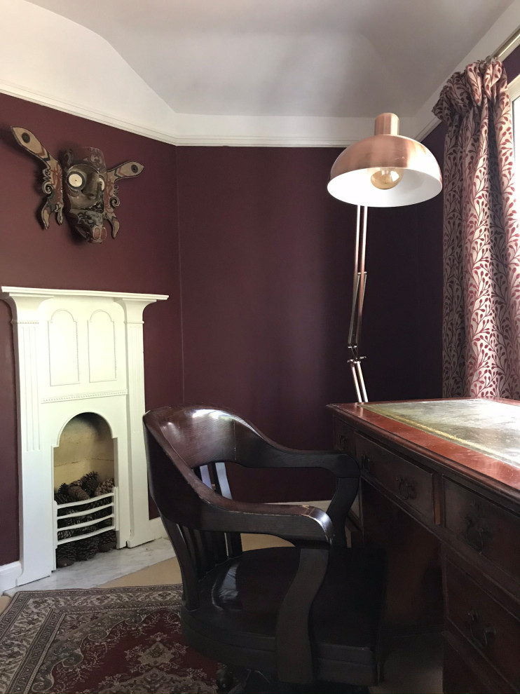Klassisk inredning av ett litet arbetsrum, med röda väggar och ett fristående skrivbord