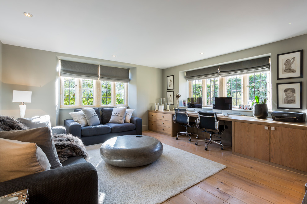 Imagen de despacho de estilo de casa de campo grande sin chimenea con paredes grises, suelo de madera en tonos medios y escritorio empotrado