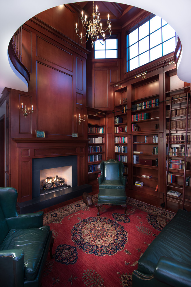 Foto på ett mycket stort vintage hemmabibliotek, med bruna väggar, mellanmörkt trägolv, en standard öppen spis och ett fristående skrivbord