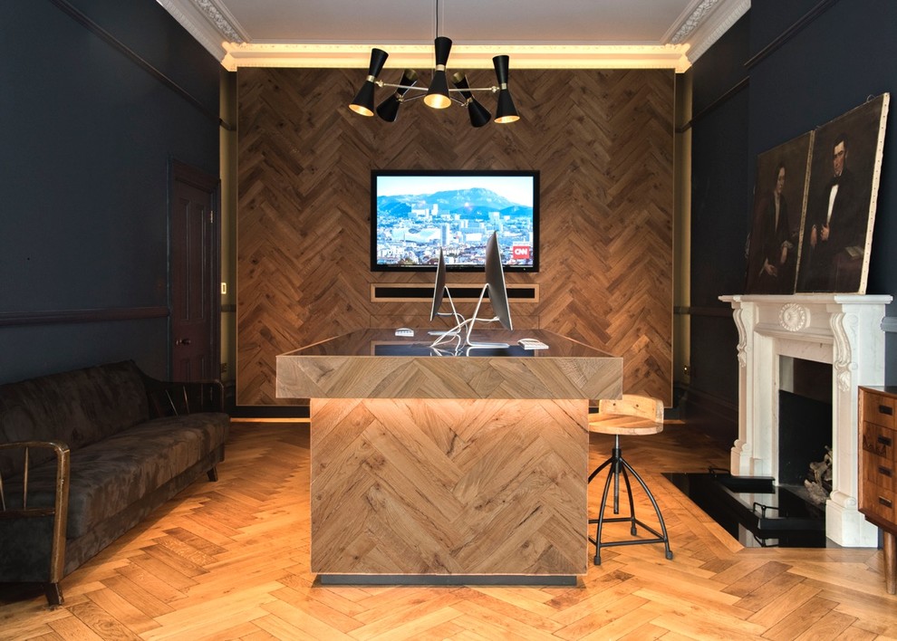 ロンドンにあるラグジュアリーな中くらいなエクレクティックスタイルのおしゃれな書斎 (青い壁、無垢フローリング、標準型暖炉、石材の暖炉まわり、自立型机、茶色い床) の写真