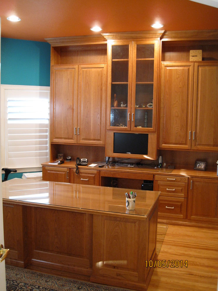 Diseño de despacho tradicional de tamaño medio sin chimenea con paredes azules, suelo de madera clara y escritorio independiente