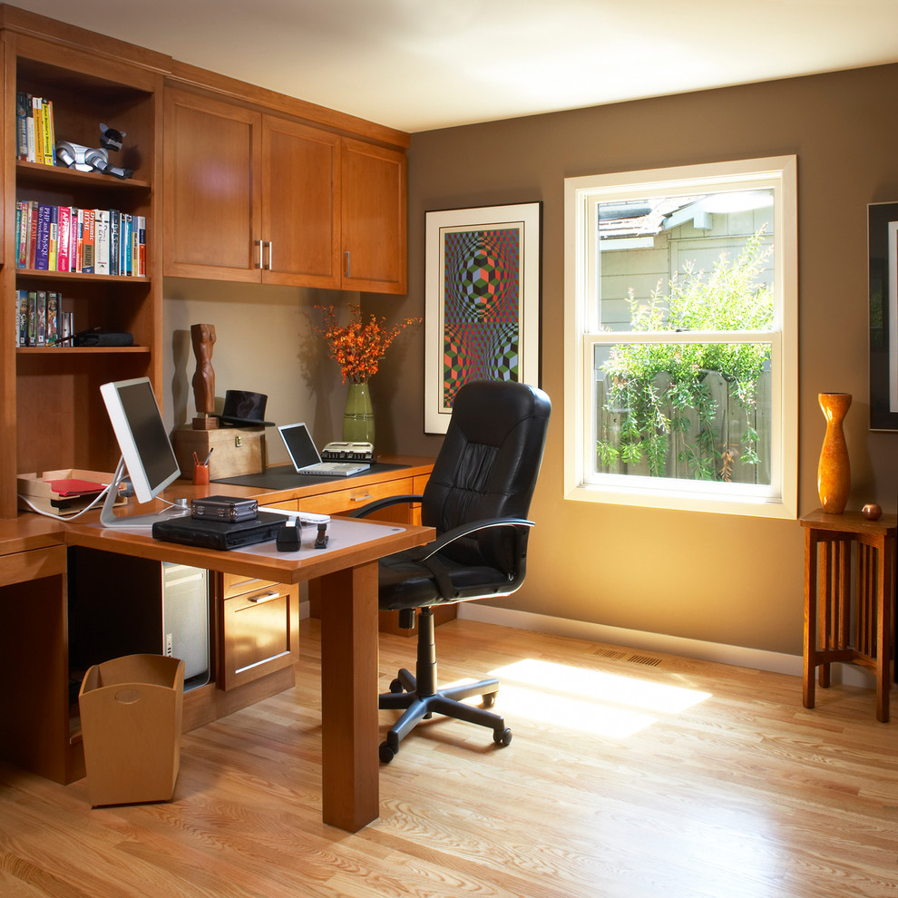 Example of a classic built-in desk medium tone wood floor home office design in San Francisco with brown walls