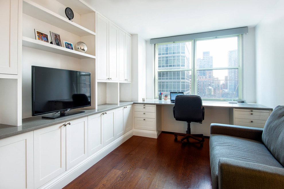Mittelgroßes Modernes Arbeitszimmer mit weißer Wandfarbe, dunklem Holzboden und Einbau-Schreibtisch in New York