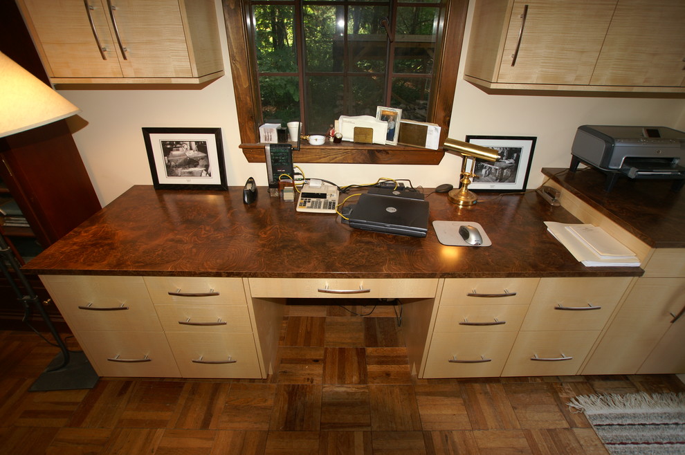 Photo of a modern home office in Boston with a built-in desk and light hardwood flooring.