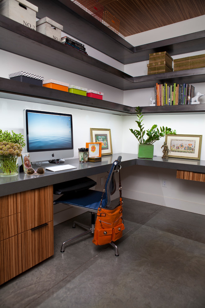 Ejemplo de despacho actual de tamaño medio sin chimenea con paredes blancas, suelo de cemento y escritorio empotrado