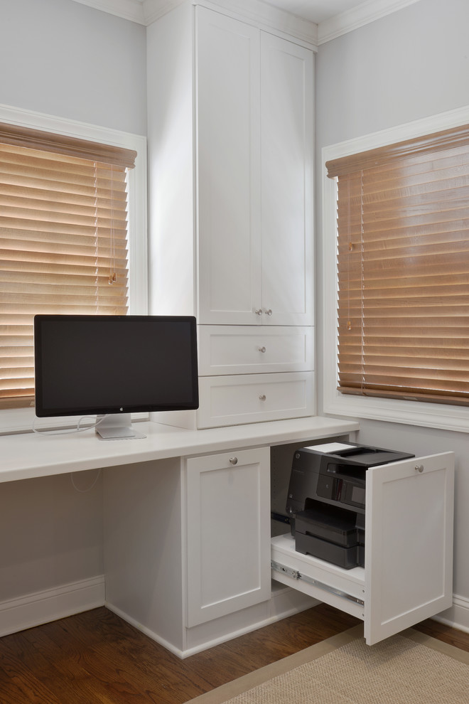 Idée de décoration pour un grand bureau design avec un mur blanc, un sol en bois brun et un bureau intégré.