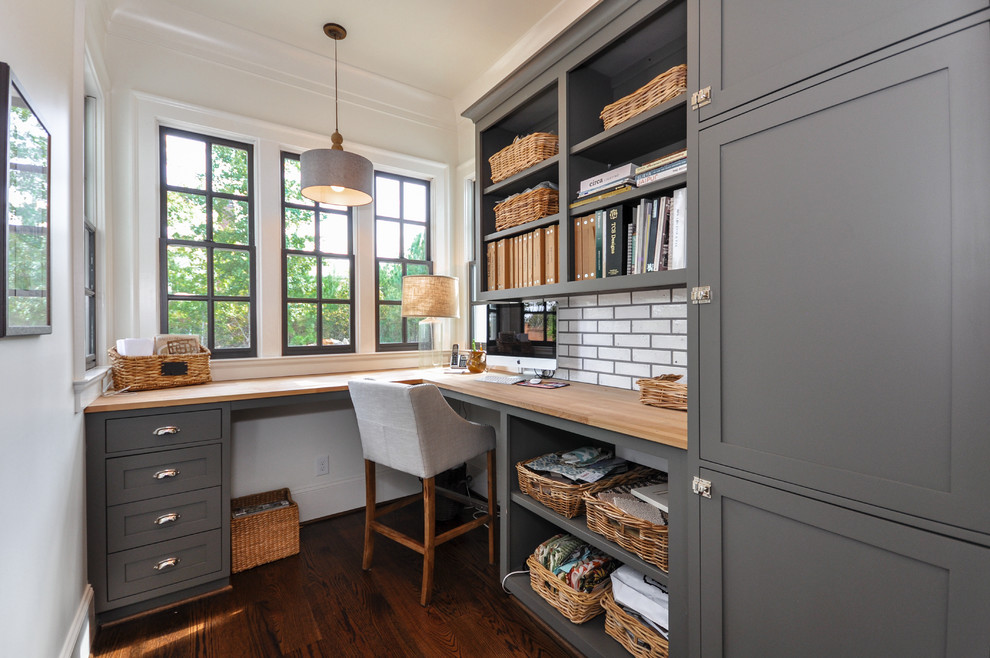 Foto de despacho actual de tamaño medio sin chimenea con paredes blancas, suelo de madera oscura, escritorio empotrado y suelo marrón