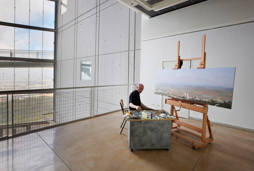 Cette photo montre un bureau industriel de type studio avec un mur blanc et sol en béton ciré.