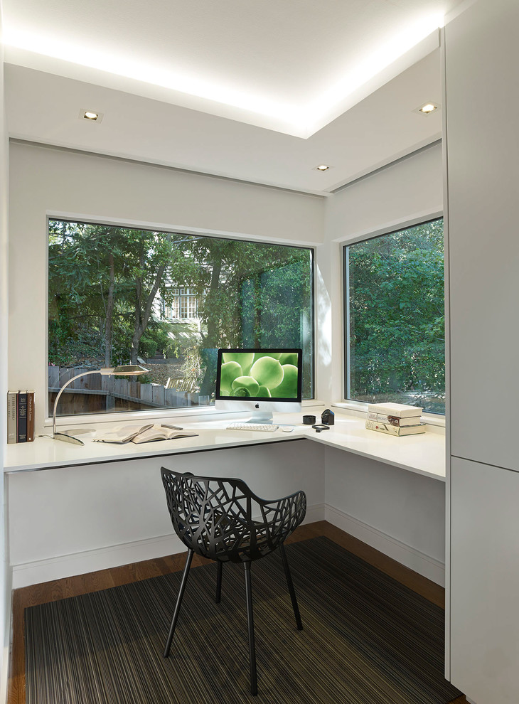 This is an example of a small modern home office in San Francisco with beige walls, carpet and a built-in desk.