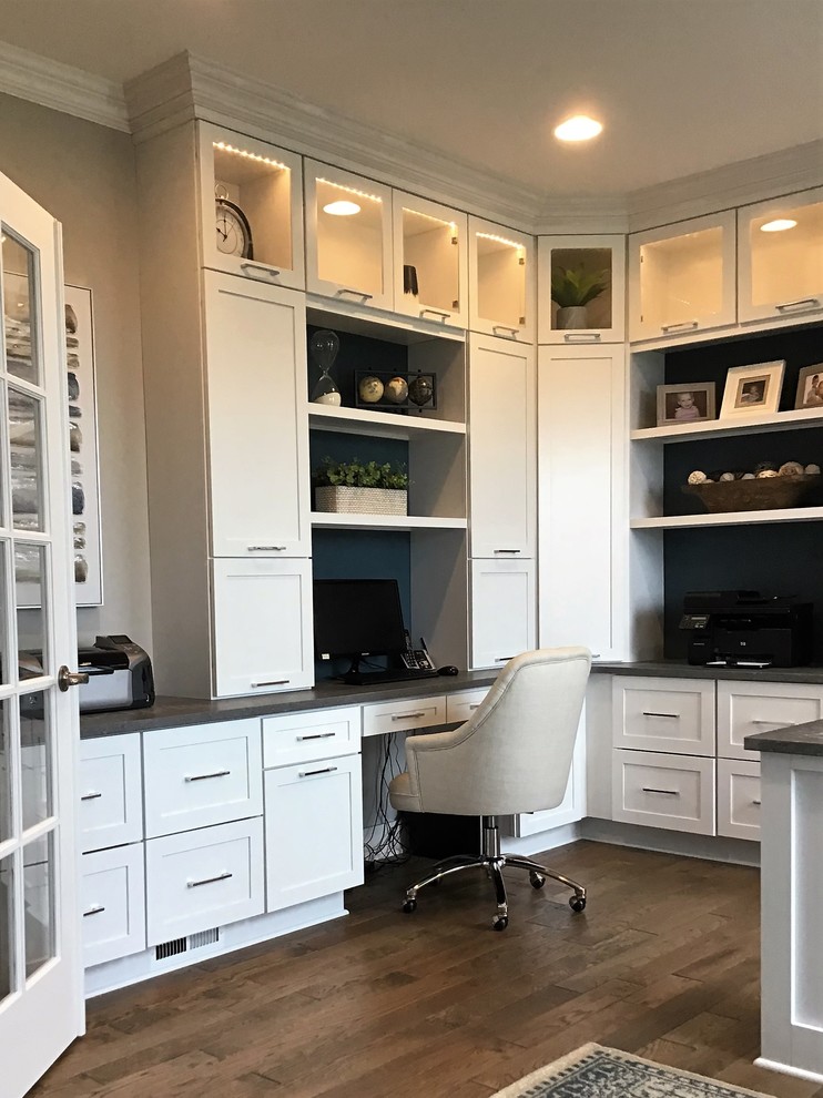 Modelo de despacho contemporáneo de tamaño medio con paredes azules, suelo de madera en tonos medios, escritorio independiente y suelo marrón