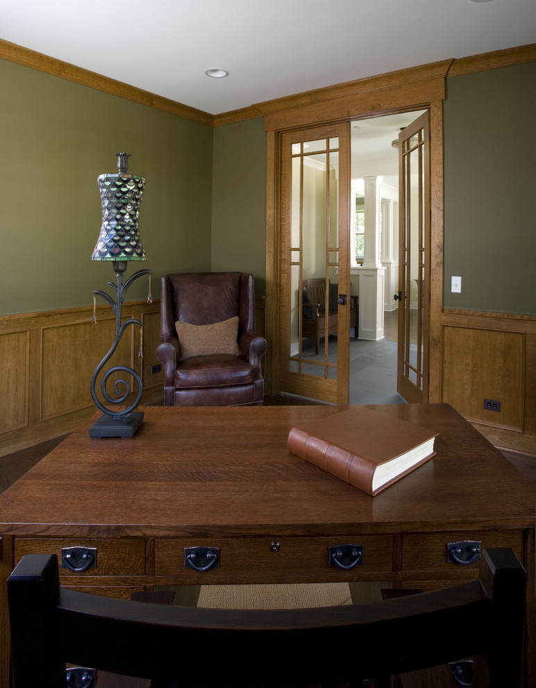 Imagen de despacho de estilo americano grande sin chimenea con paredes verdes, suelo de madera en tonos medios, escritorio independiente, suelo marrón y panelado