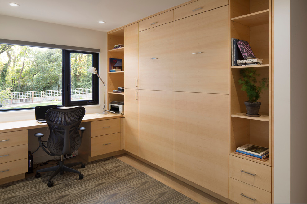 Modelo de despacho minimalista de tamaño medio con paredes blancas, suelo de madera clara y escritorio empotrado