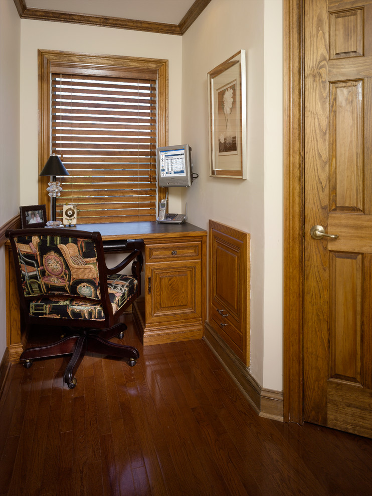 Cette photo montre un petit bureau sud-ouest américain de type studio avec un mur beige, aucune cheminée, un bureau intégré et un sol en bois brun.