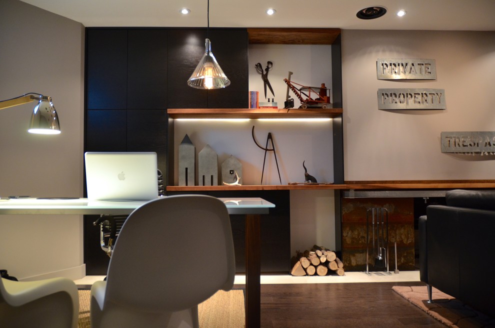 Diseño de despacho actual de tamaño medio con paredes grises, suelo de madera oscura, escritorio independiente y suelo marrón