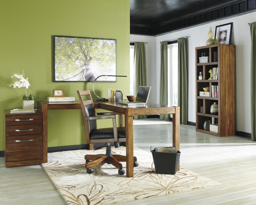 Foto på ett arbetsrum, med gröna väggar, mellanmörkt trägolv och ett fristående skrivbord