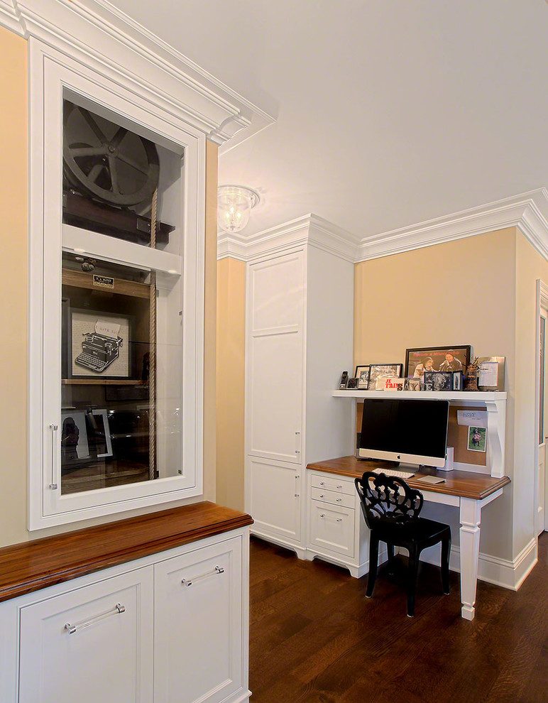 Imagen de despacho blanco tradicional con paredes beige, suelo de madera oscura, escritorio empotrado y suelo marrón