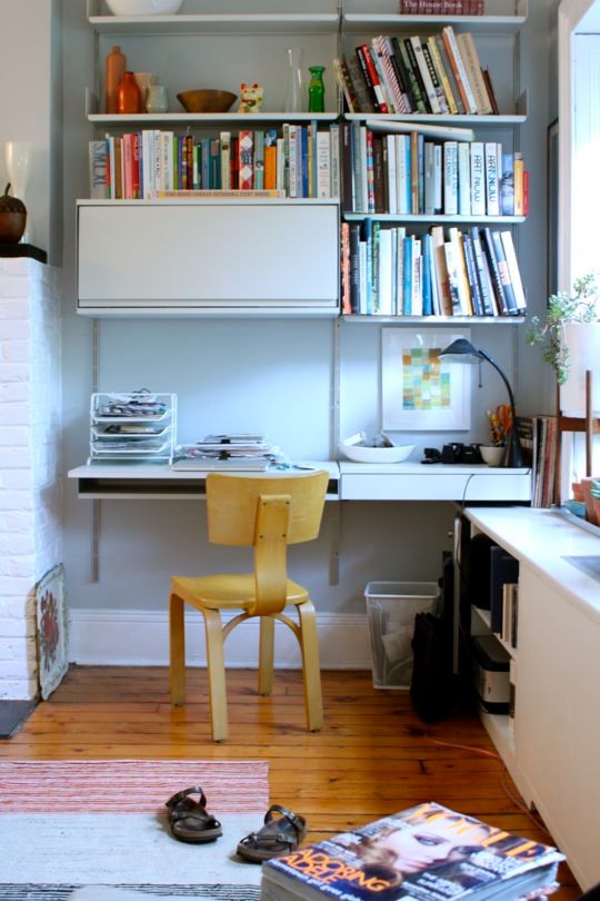 Inredning av ett litet hemmastudio, med ett inbyggt skrivbord, grå väggar och ljust trägolv