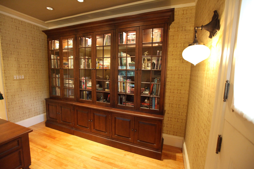 Diseño de despacho beige clásico de tamaño medio con biblioteca, paredes beige, suelo de madera en tonos medios, escritorio independiente y suelo marrón