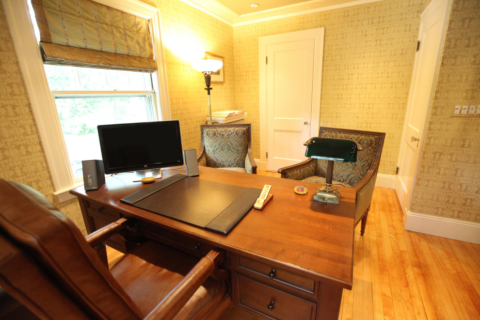 Imagen de despacho beige tradicional de tamaño medio con biblioteca, paredes beige, suelo de madera en tonos medios, escritorio independiente y suelo marrón