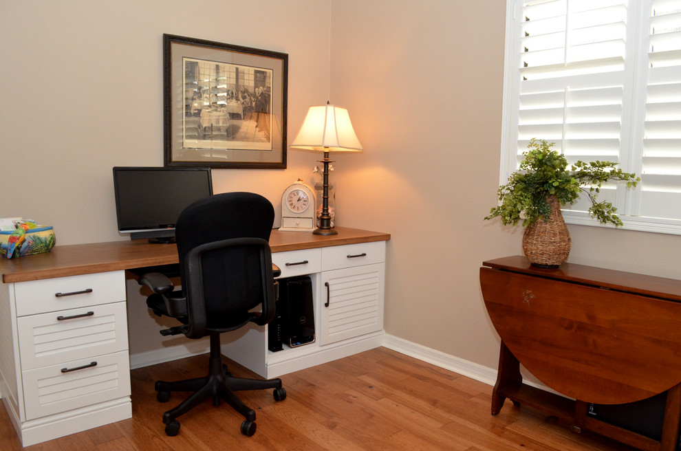 Diseño de despacho tradicional de tamaño medio sin chimenea con paredes beige, suelo de madera en tonos medios y escritorio empotrado