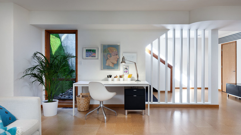 Идея дизайна: большой кабинет в современном стиле с белыми стенами, пробковым полом и отдельно стоящим рабочим столом без камина