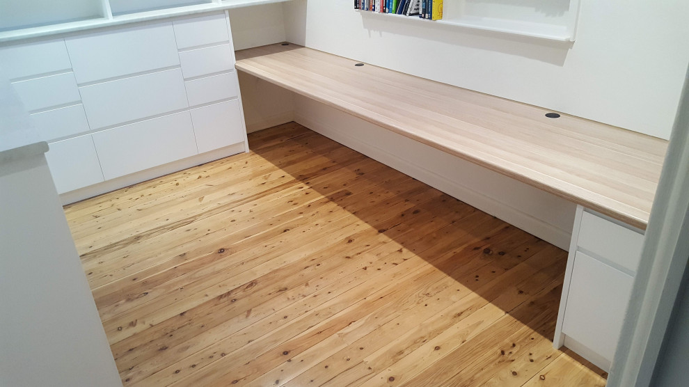 Medium sized modern study in Sydney with beige walls, medium hardwood flooring, a built-in desk and brown floors.