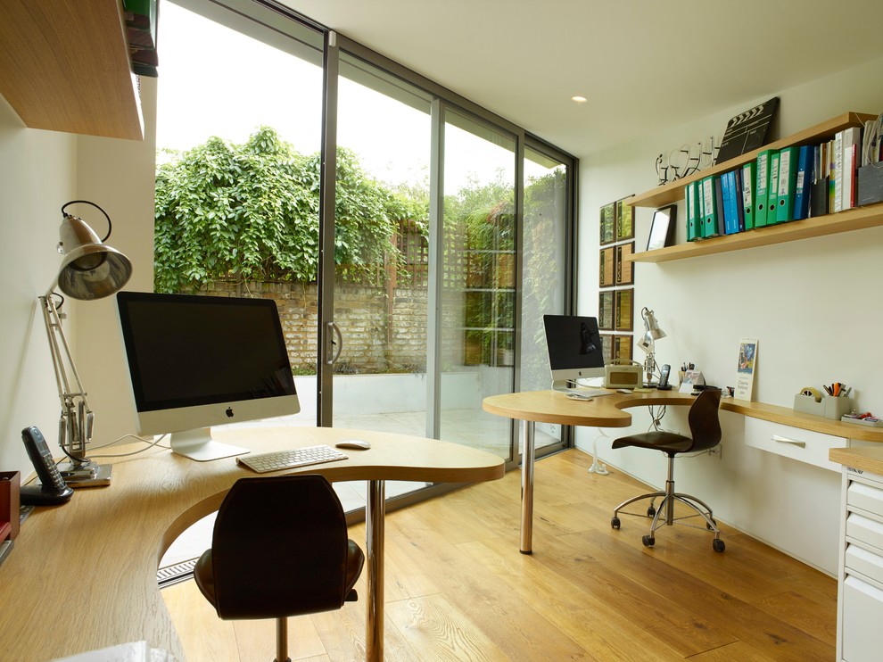 Small contemporary home office in London with white walls, light hardwood flooring and a built-in desk.