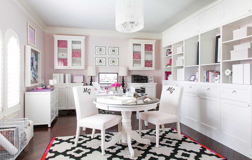 Foto på ett stort funkis hemmastudio, med rosa väggar, mörkt trägolv och ett fristående skrivbord