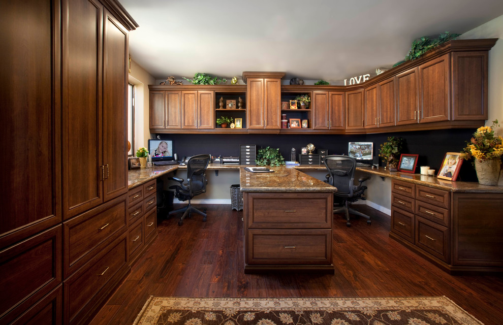 Modelo de despacho clásico grande sin chimenea con paredes beige, suelo de madera oscura y escritorio empotrado