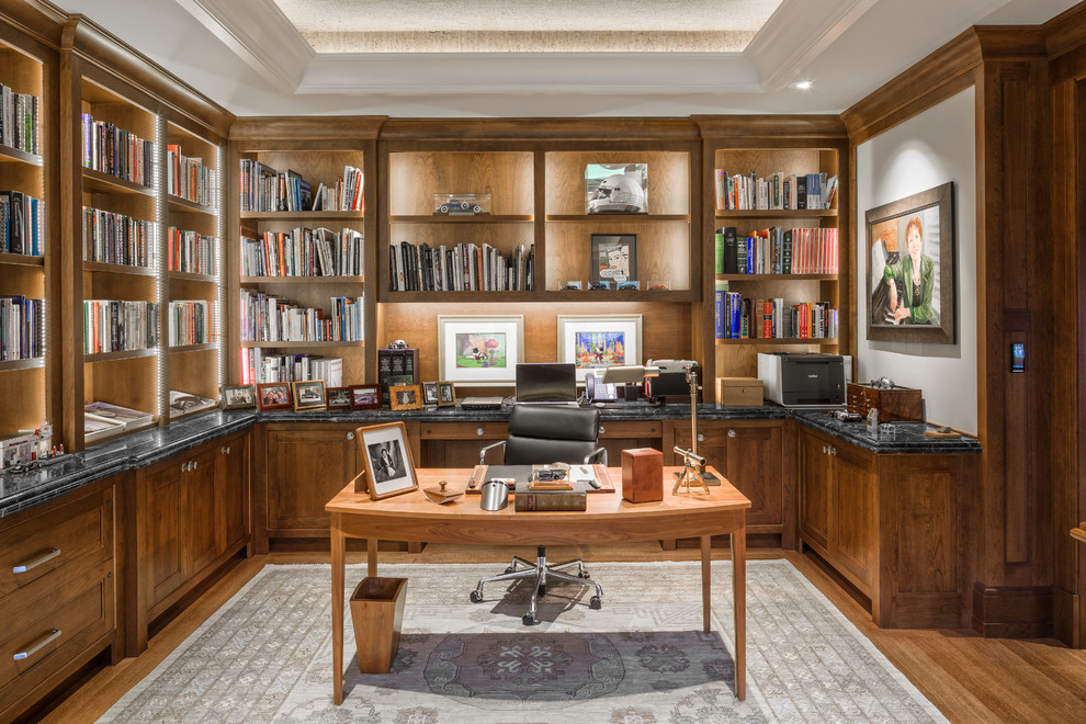 Exempel på ett stort klassiskt arbetsrum, med grå väggar, mellanmörkt trägolv, ett fristående skrivbord, brunt golv och ett bibliotek