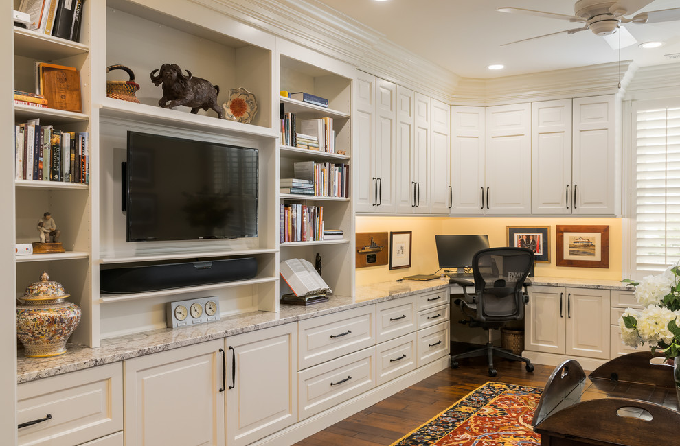 Modelo de despacho clásico grande con paredes beige, suelo de madera en tonos medios, escritorio empotrado y suelo marrón