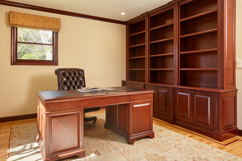 Idéer för vintage hemmabibliotek, med beige väggar, mellanmörkt trägolv och ett fristående skrivbord